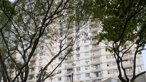 Un immeuble à plusieurs étages doté d’un garage, entouré d’arbres.