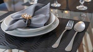 Une table à manger dressée avec des assiettes, des verres, des couverts et une serviette.