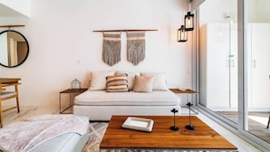 Camera da letto moderna con divano letto, tavolino in legno, uno specchio e vista esterna.