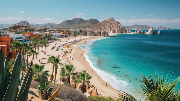 Una spiaggia con acque cristalline turchesi, palme e montagne sullo sfondo.