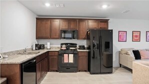 A kitchen with wooden cabinets, a black refrigerator, a microwave, a stove, and a dishwasher. - Charming house in Ferris (Ferris)