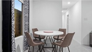 A modern dining area with a round table and six chairs, a patterned curtain, and a view of the outside. - Charming house in Ferris (Ferris)