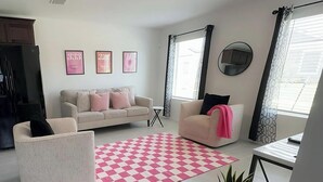 A living room with a checkered rug, a sofa, a chair, a small table, and a potted plant. - Charming house in Ferris (Ferris)