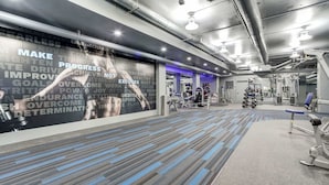 Une salle de sport équipée de matériel d’exercice, ornée d’affiches motivantes et dotée d’un tapis à motifs.