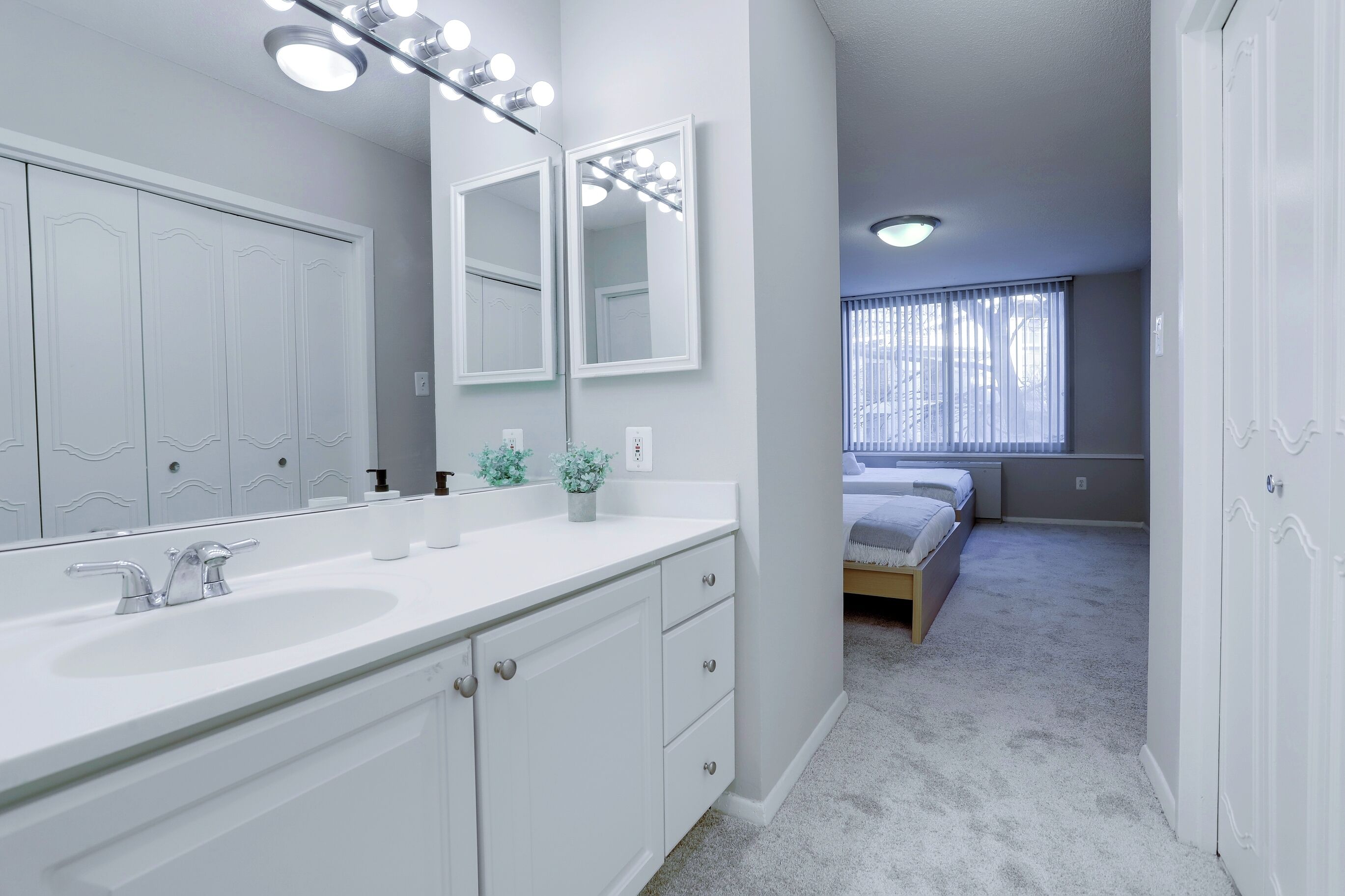 Une salle de bain moderne avec un grand miroir, un meuble-lavabo et un dressing.