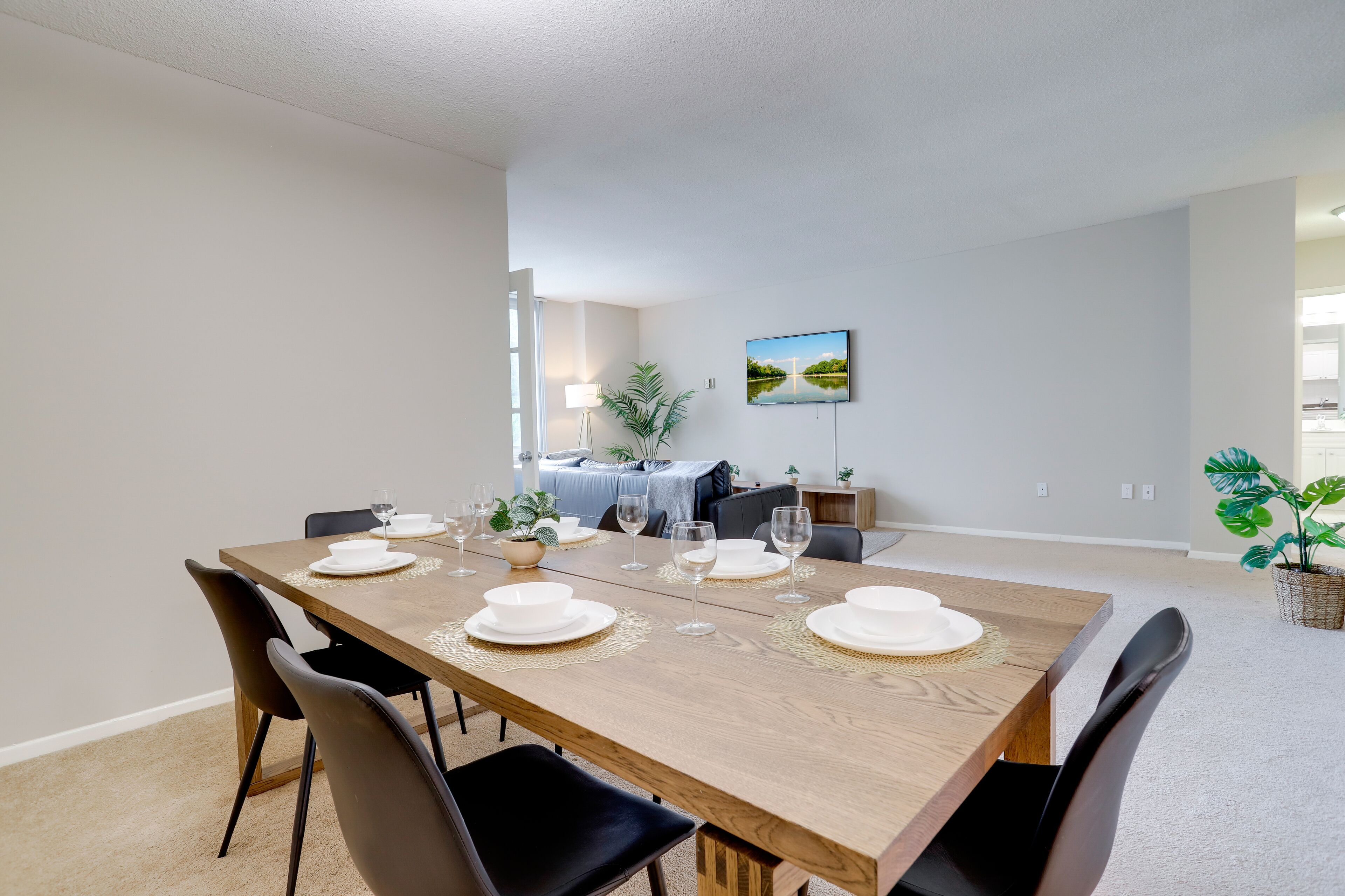 Comedor con mesa de madera preparada para cuatro personas, rodeado de sillas.