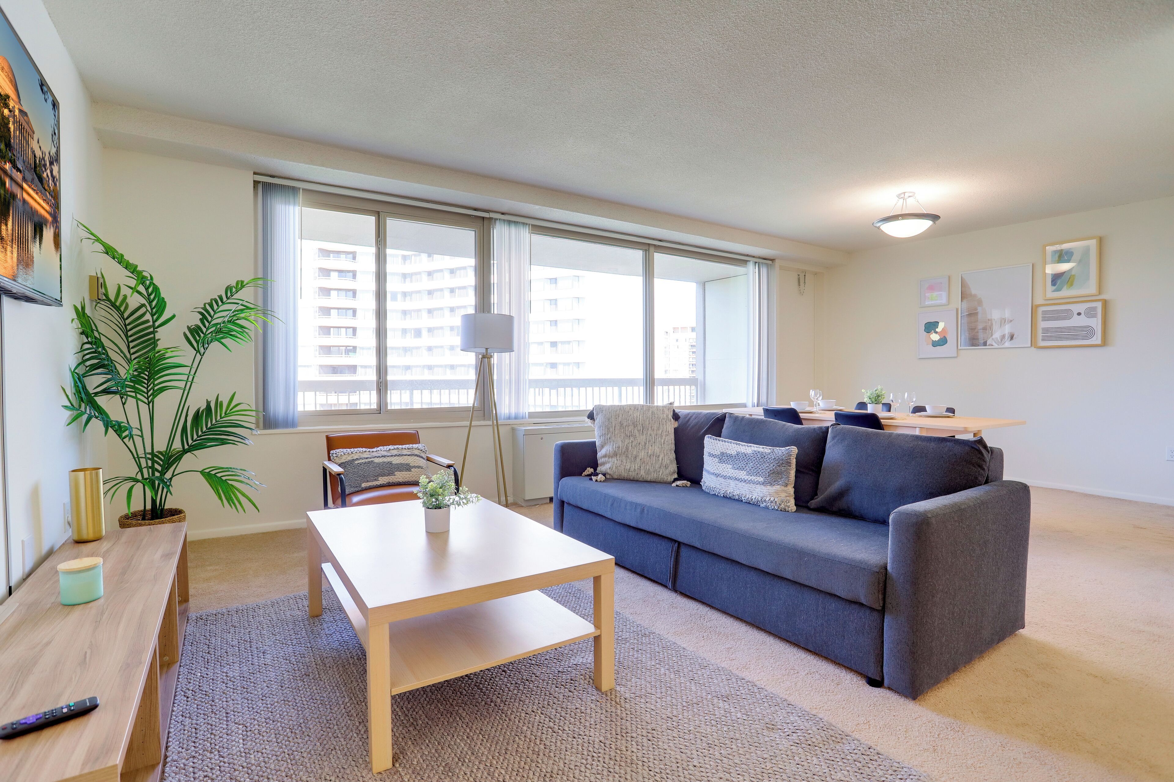 Ein modernes Wohnzimmer mit einer Couch, einem Couchtisch und einem großen Fenster mit Blick auf Gebäude.