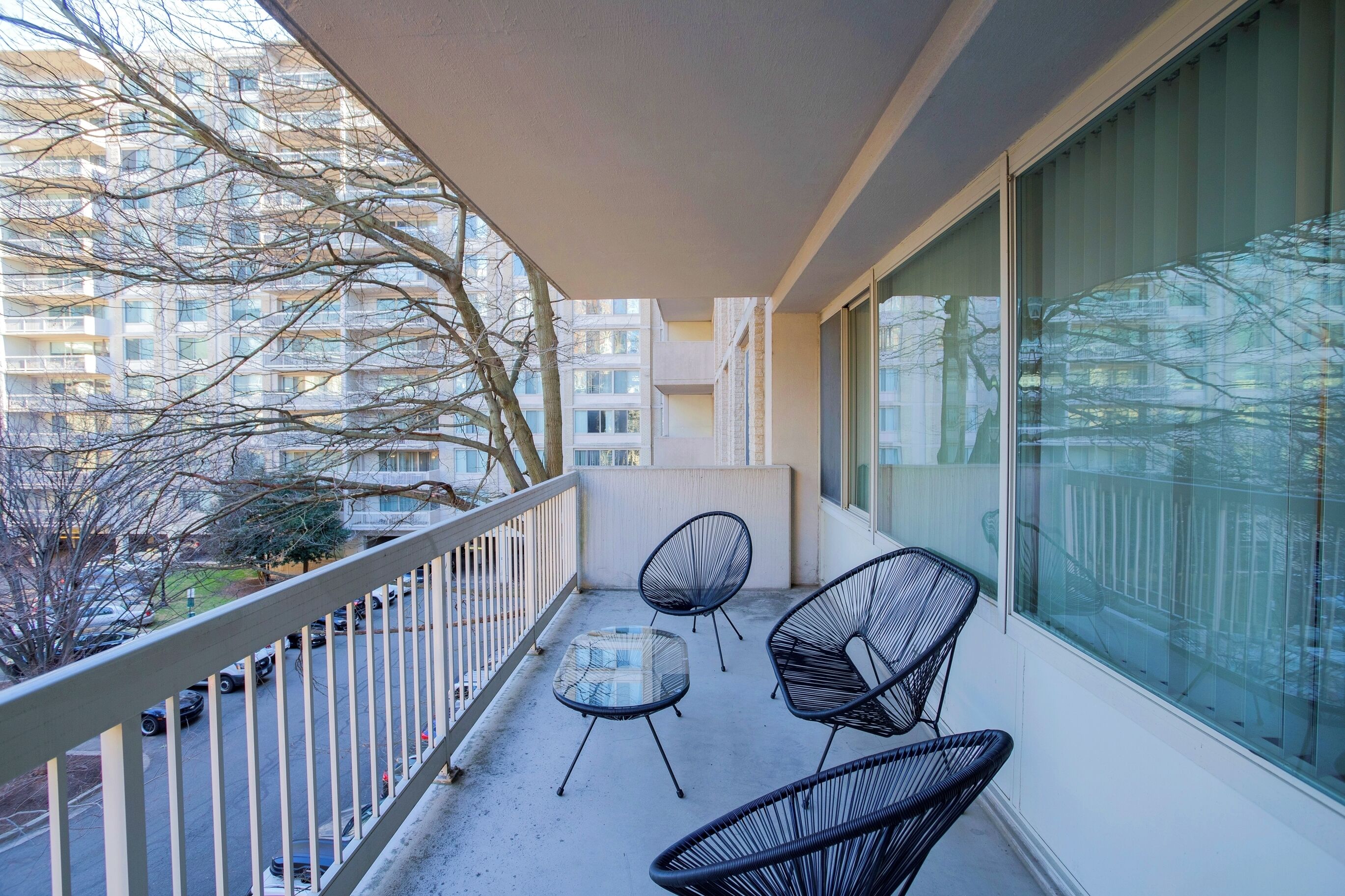 Un balcon avec une table et des chaises, une vue sur le paysage urbain et une balustrade.