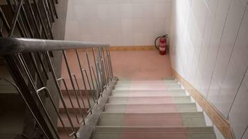 Una escalera con barandillas metálicas y un extintor en la pared.