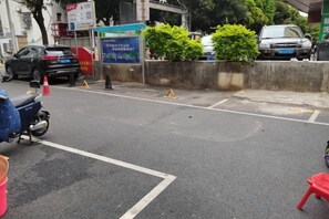 A street with a motorcycle parked on the side, a red plastic chair, and a blue bucket. - Nanning Tianli Hotel (Nanning)