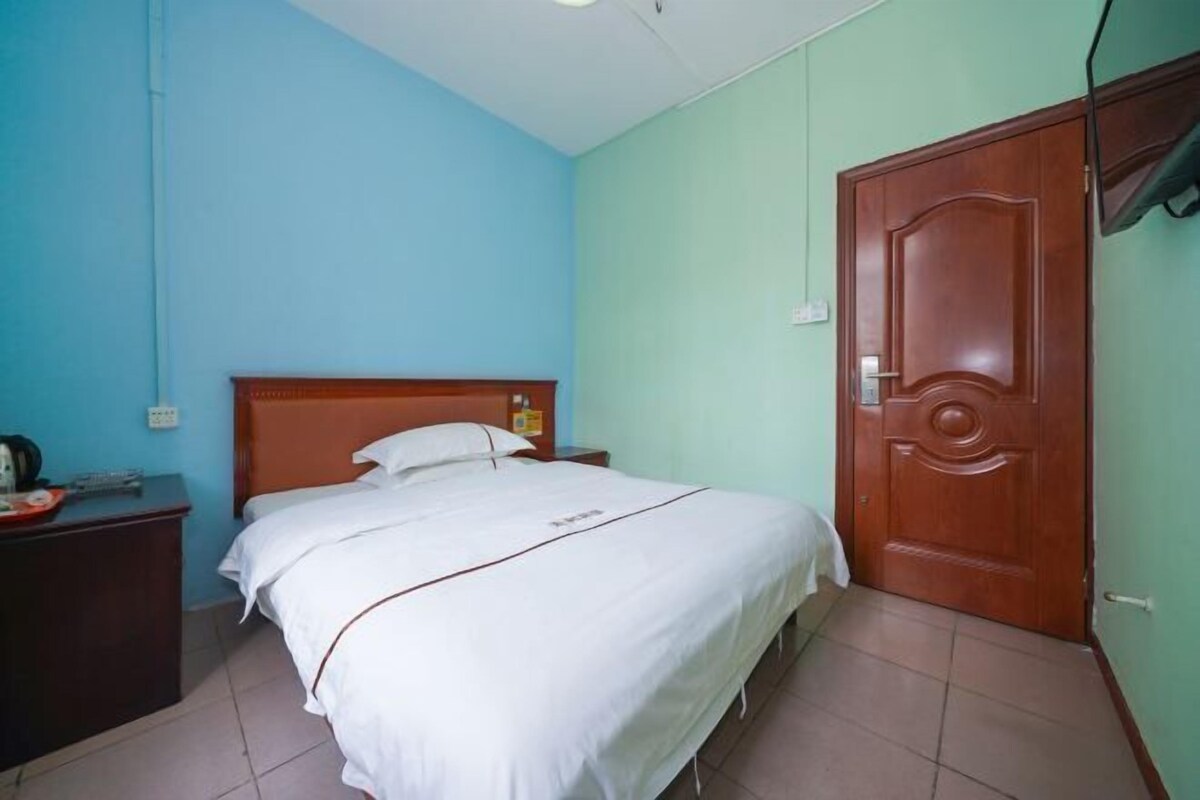 Een kamer met een bed, een houten deur en een nachtkastje met een lamp.