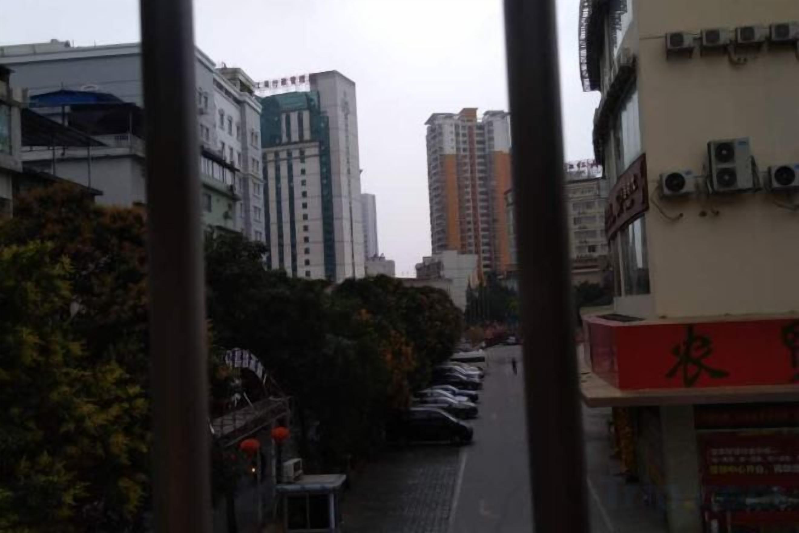 Une vue de rue avec des immeubles, des voitures garées et un ciel dégagé.
