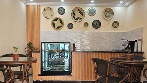 A restaurant with a modern interior, featuring a central counter, wooden paneling, and decorative plates on the wall. - Calm Corner Addis  (Addis Ababa)