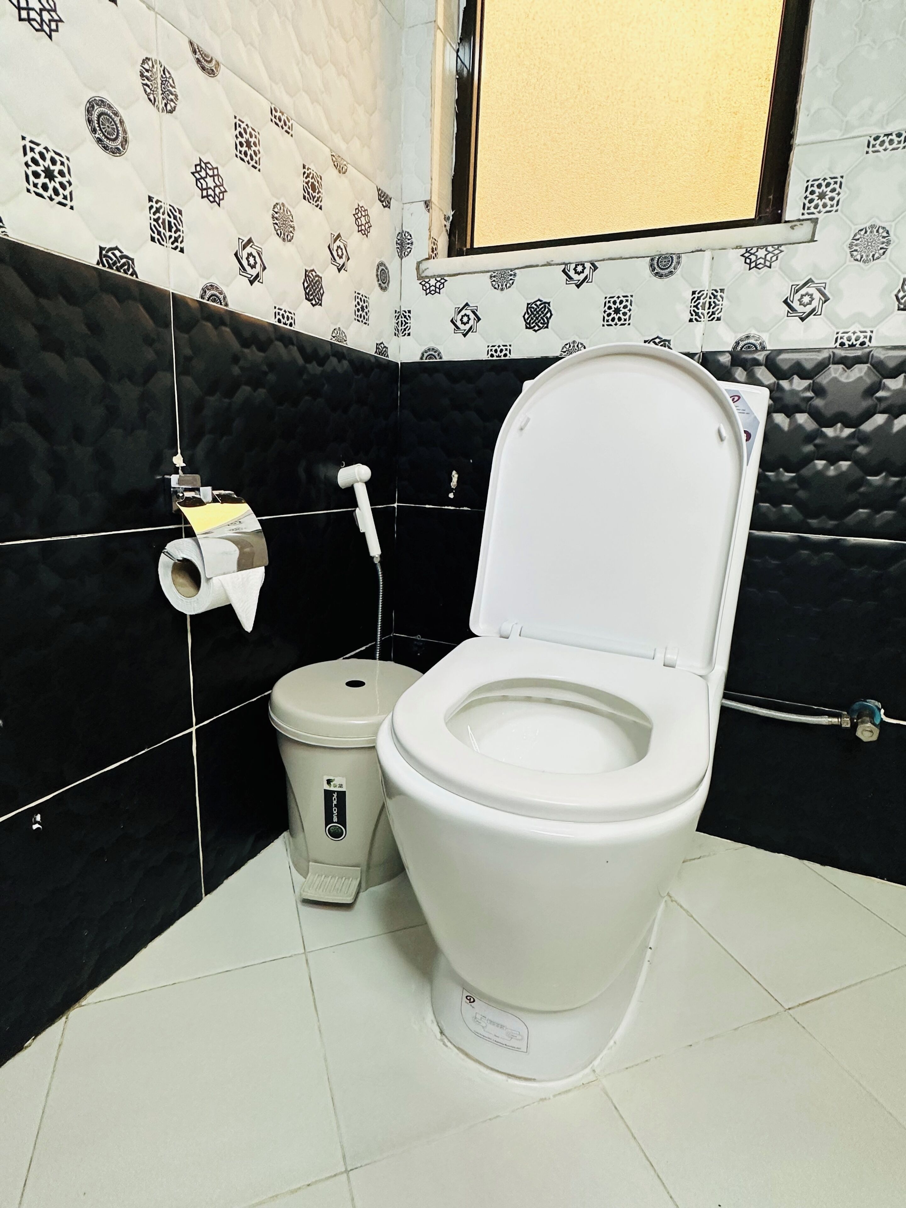 A bathroom with a toilet, bidet, and toilet paper holder.
