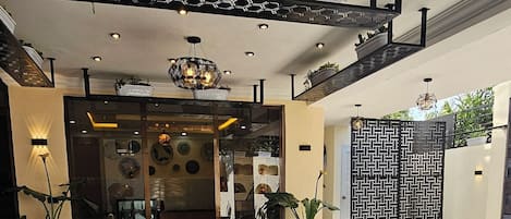 Eine Lobby mit gemusterten Bodenfliesen, Holzstühlen und einer dekorativen Decke.