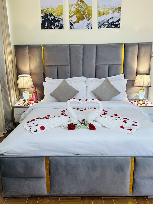A neatly made bed with a white bedspread, two pillows, and a decorative swan made of towels and rose petals. - Calm Corner Addis (Addis Ababa)