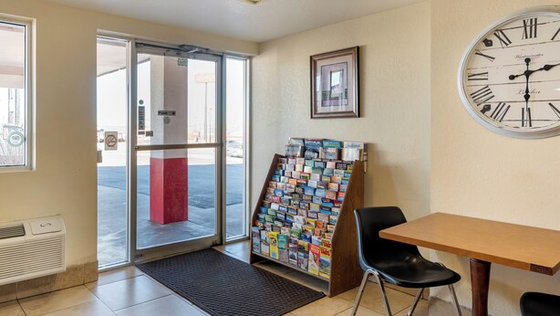 A hotel lobby with a reception desk, a clock, a framed picture, and a magazine rack. - Pueblo Inn (Pueblo)