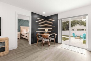A modern room with a dining area, a bed, and a view of the outdoors. - Santos Place -New Built Home -4Mins To Trailhead- Centrally Located! (Ocala)