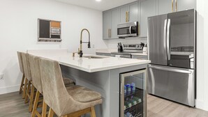 A modern kitchen with a central island, stainless steel appliances, and bar stools. - Santos Place -New Built Home -4Mins To Trailhead- Centrally Located! (Ocala)