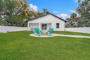 A house with a covered patio, a small fire pit, and a white fence. - Santos Place -New Built Home -4Mins To Trailhead- Centrally Located! (Ocala)