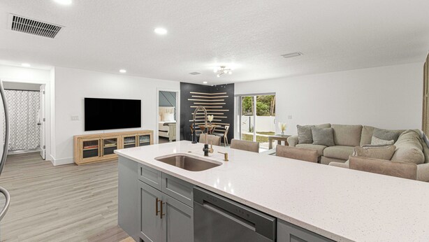 A modern kitchen with a central island, built-in appliances, and a large window providing natural light. - Santos Place -New Built Home -4Mins To Trailhead- Centrally Located! (Ocala)