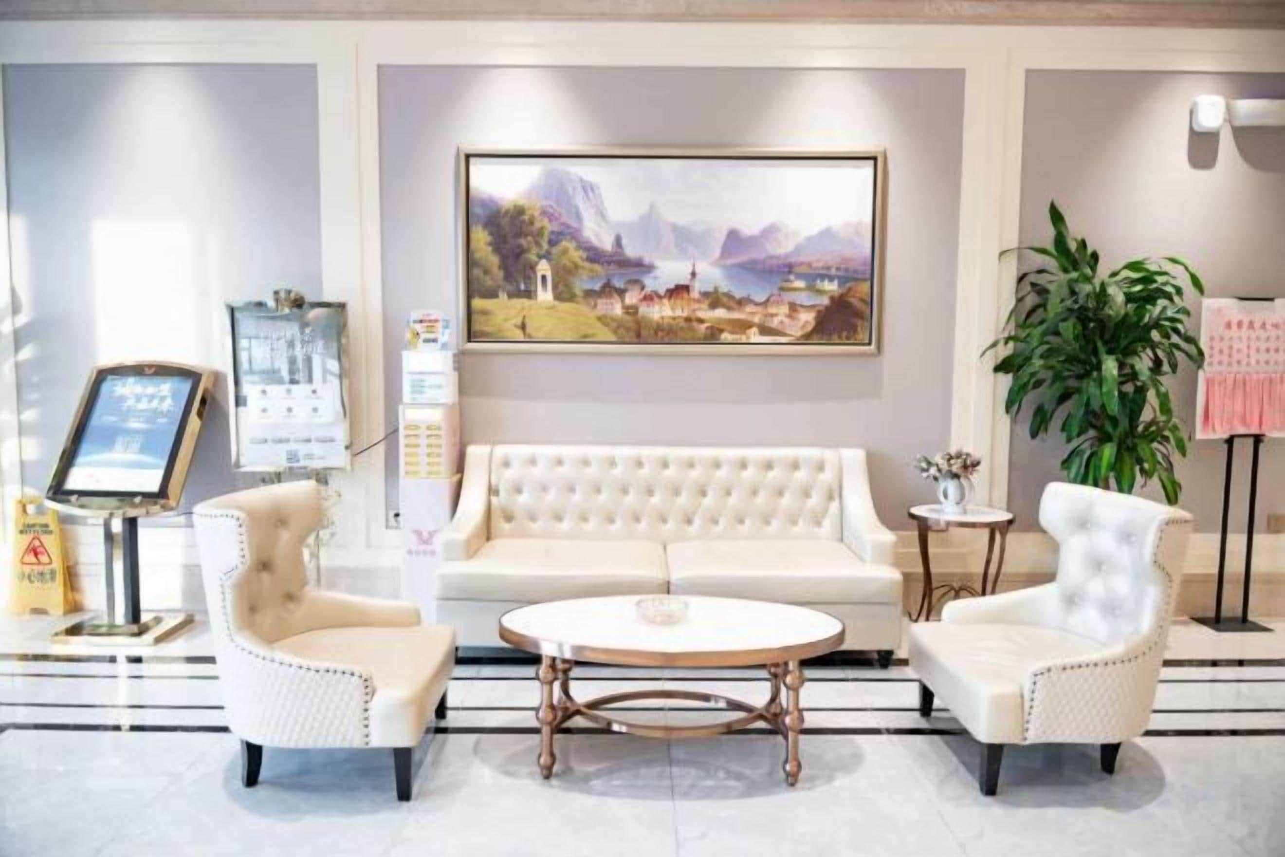 Een hotel lobby met een groot schilderij, een receptiebalie, een bank, twee fauteuils en een salontafel.