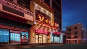A hotel with a prominent neon sign, large windows, and a modern facade. - Vienna Hotel (Jinan Huayuan Road ) (Jinan)