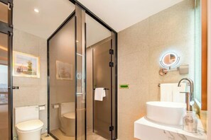 A modern bathroom with a glass-enclosed shower, a toilet, a sink with a marble countertop, and a mirror with a light. - Vienna Hotel (Jinan Huayuan Road ) (Jinan)