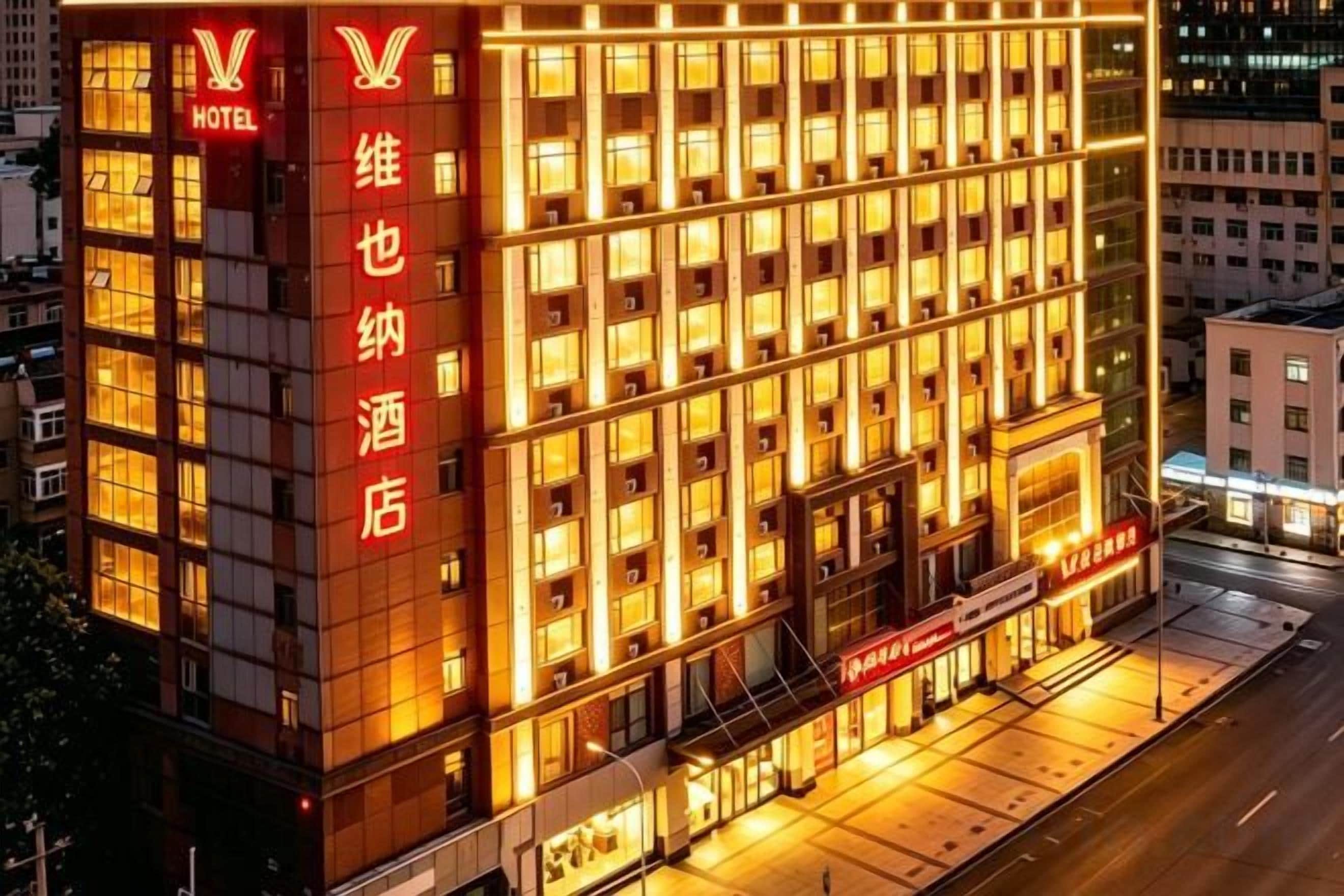 A hotel building with multiple floors, a prominent entrance, and illuminated signage.