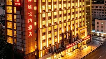 A hotel building with multiple floors, a prominent entrance, and illuminated signage.