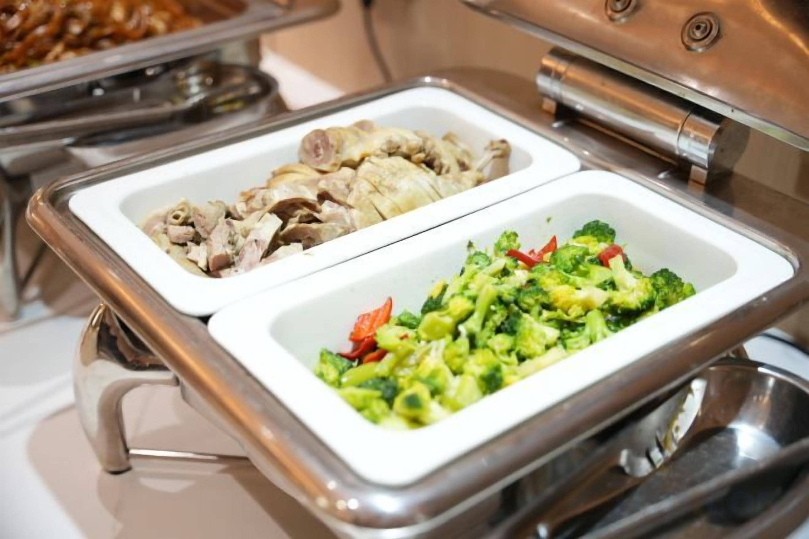 Ein Buffet mit zwei Schalen, eine mit geschnittenem Fleisch und die andere mit Gemüse.