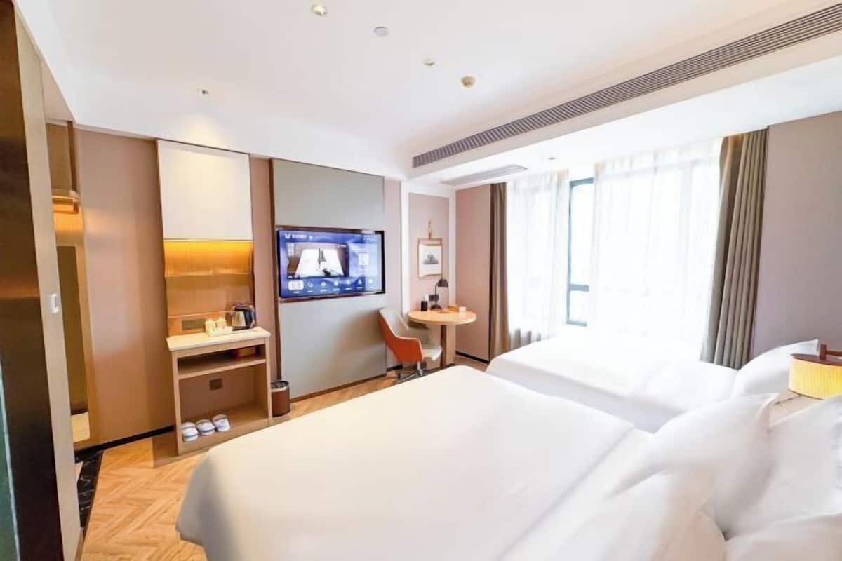Une chambre d’hôtel avec deux lits, une télévision, un bureau et une chaise.