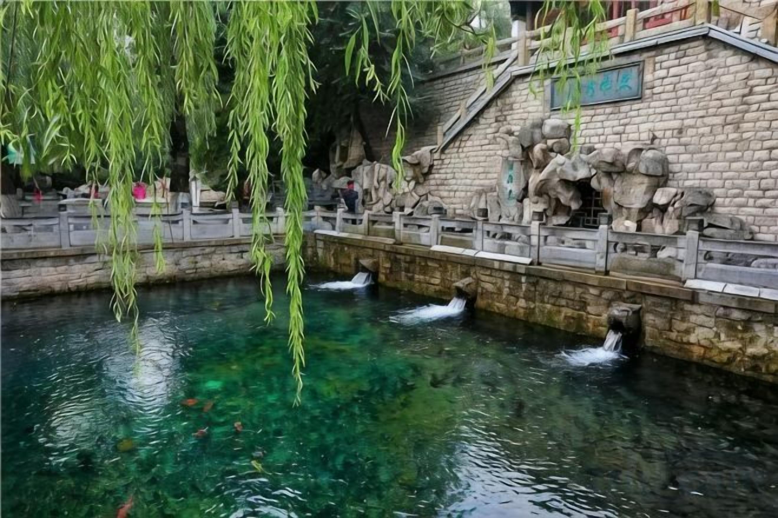 A clear water feature with a stone wall and a bridge.