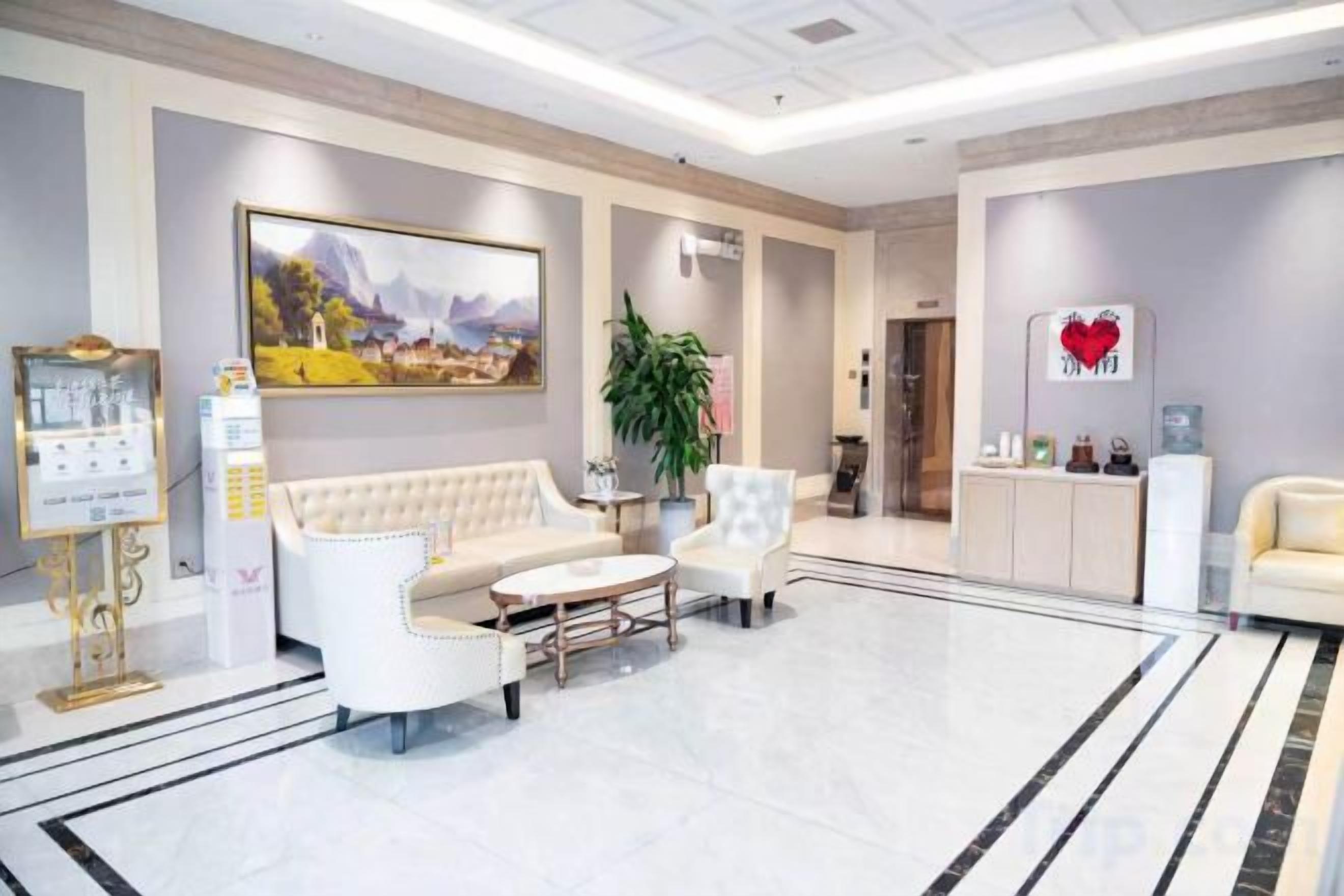A hotel lobby with a reception desk, seating area, and a large painting on the wall.