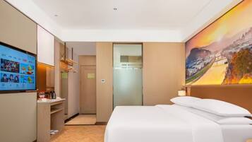 Habitación de hotel con cama, televisor mostrando un video, un cuadro en la pared y suelo de madera.