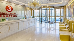 A hotel reception area with a modern design, featuring a reception desk, a chandelier, and a seating area with yellow chairs. - Vienna Hotel (Jinan Huayuan Road ) (Jinan)