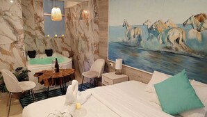 A hotel room with a bed, a painting of horses, a desk with a chair, a small table with a bottle, and a bathtub. - Hotel con garage en Cusco  (Cusco)