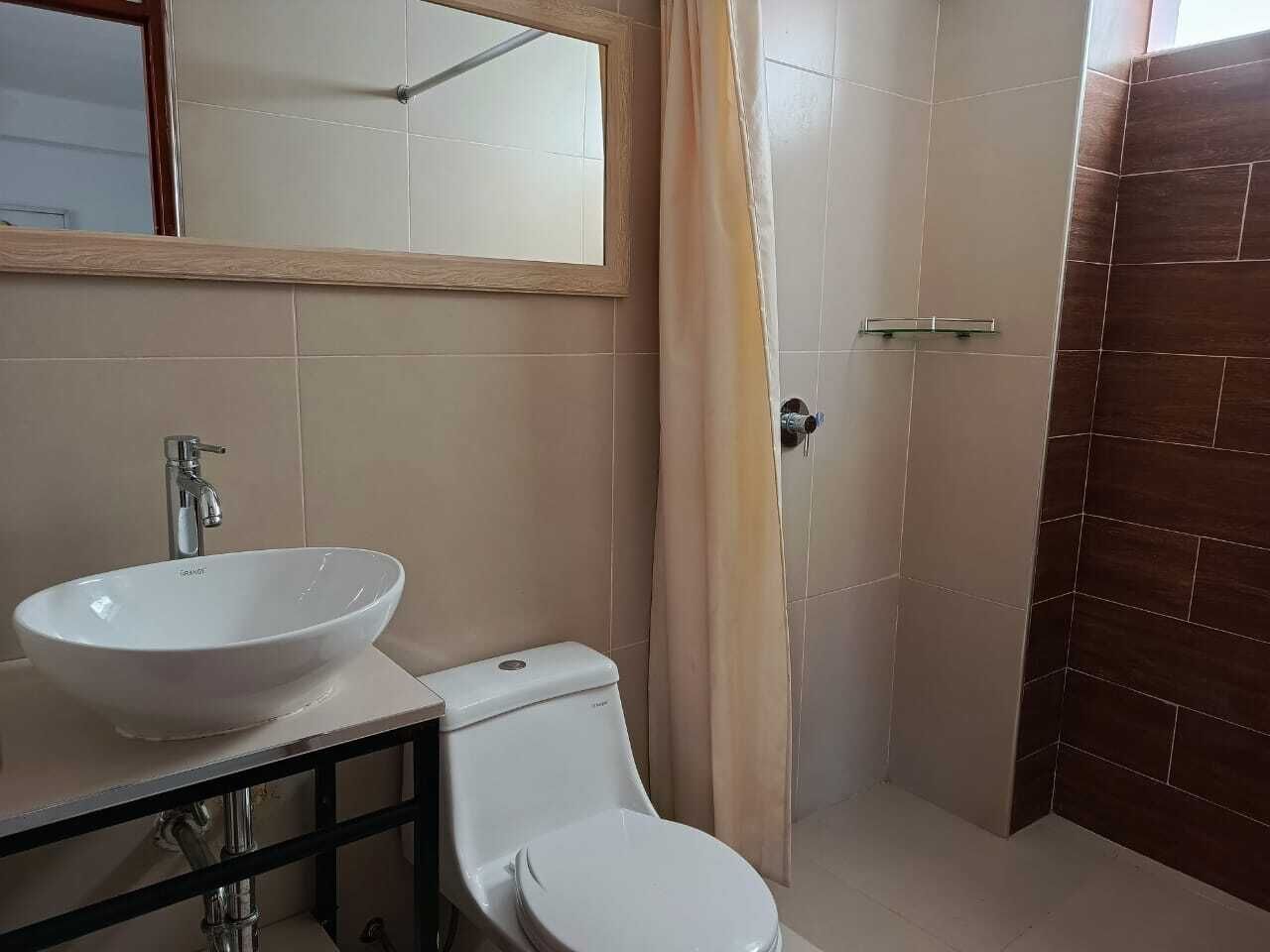 Une salle de bain avec un lavabo, des toilettes et un miroir, le tout de couleur blanche.