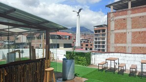 A rooftop terrace with artificial grass, a wooden stool, and tables. - Hotel con garage en Cusco  (Cusco)