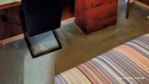 Un dormitorio con una cama, un escritorio con televisor, una silla y un aparador.