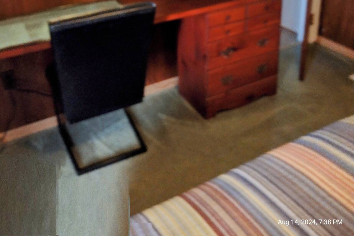 A bedroom with a bed, a desk with a television, a chair, and a dresser.