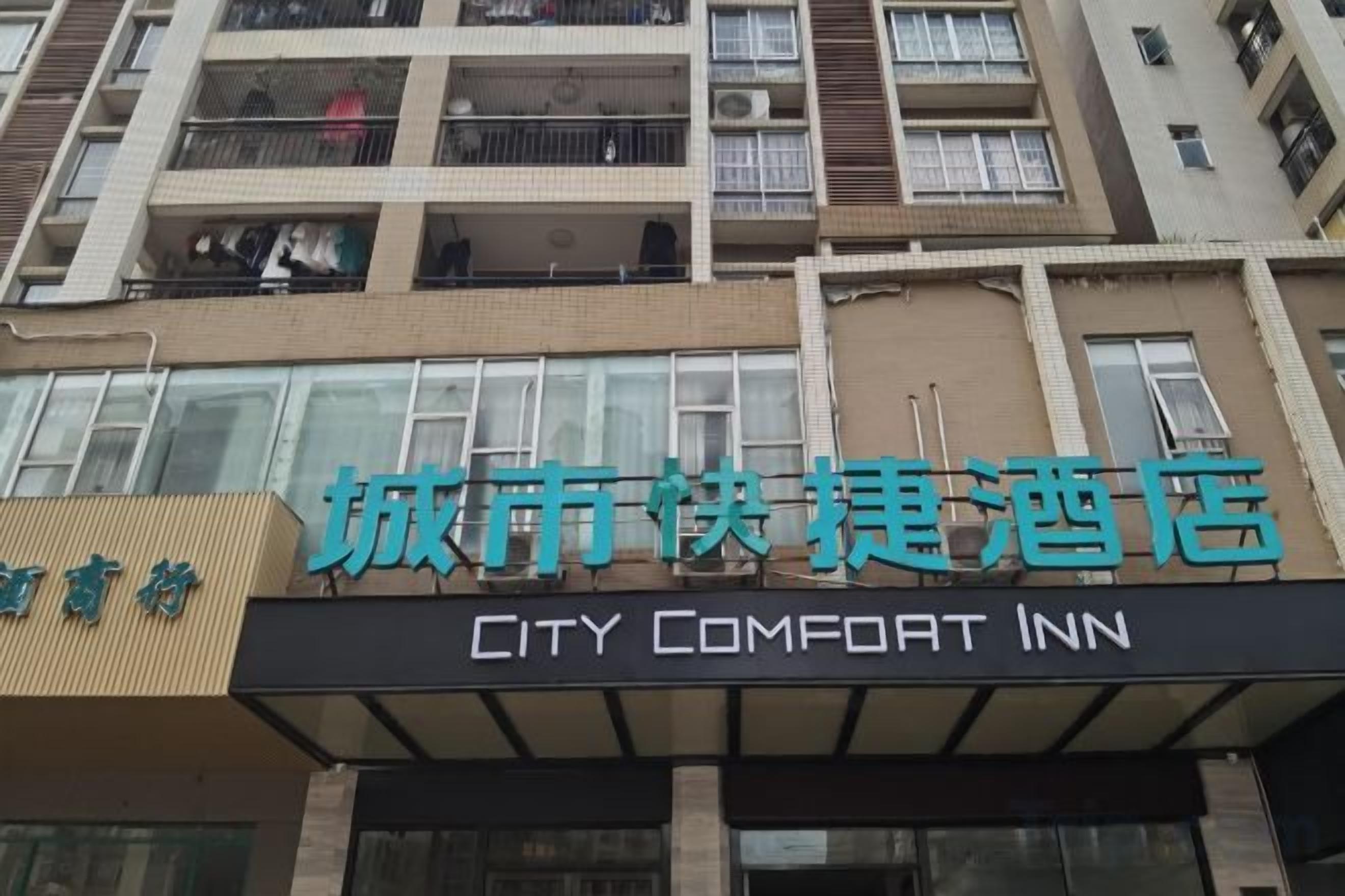 Un hotel con un cartel que dice 'CITY COMFORT INN' y un cartel más pequeño encima que dice 'City Comfort Inn'.