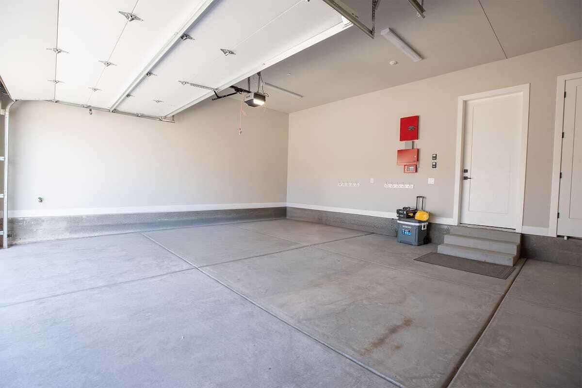 Een ruime, overdekte ruimte met een vlakke plafond, een deur en een klein trapje dat naar een hoger niveau leidt.