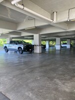 Garagem de estacionamento em vários níveis, com pilares de concreto e tubulações no teto.