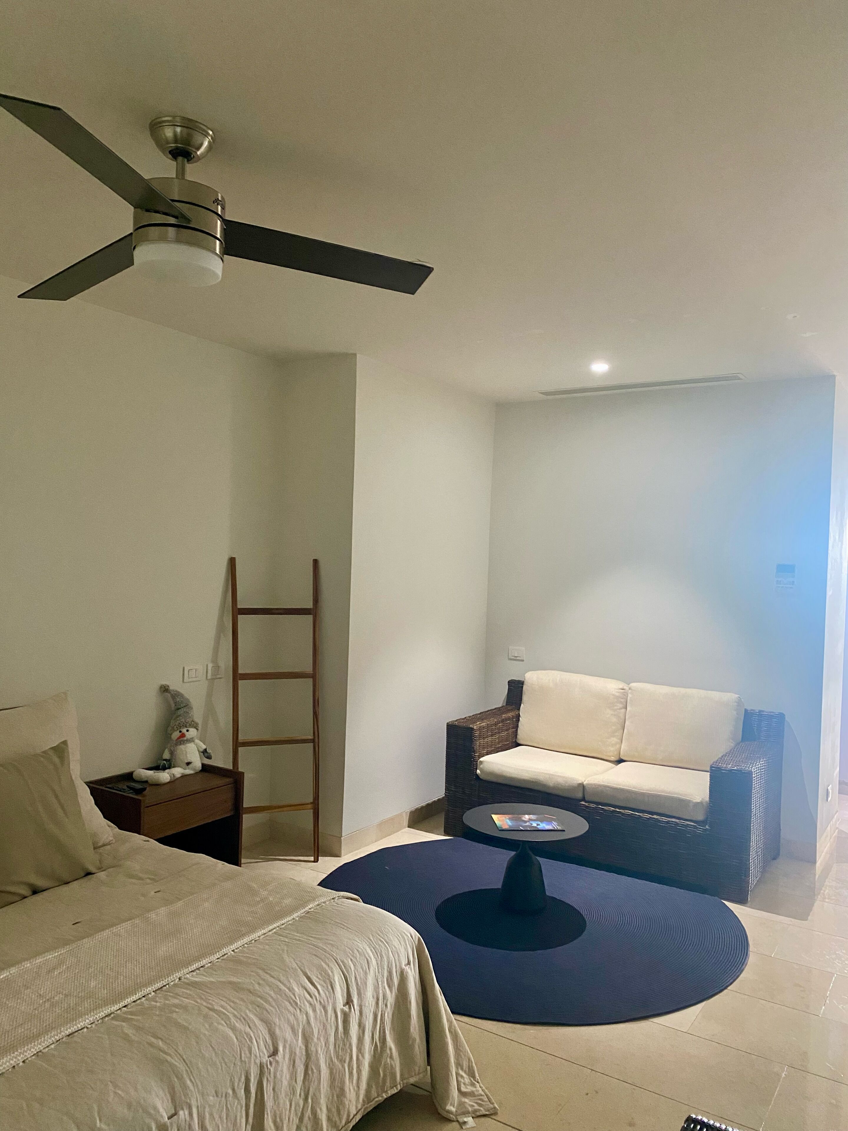 A bedroom with a bed, a nightstand, a dresser, a ceiling fan, a chair, a small table, and a window.