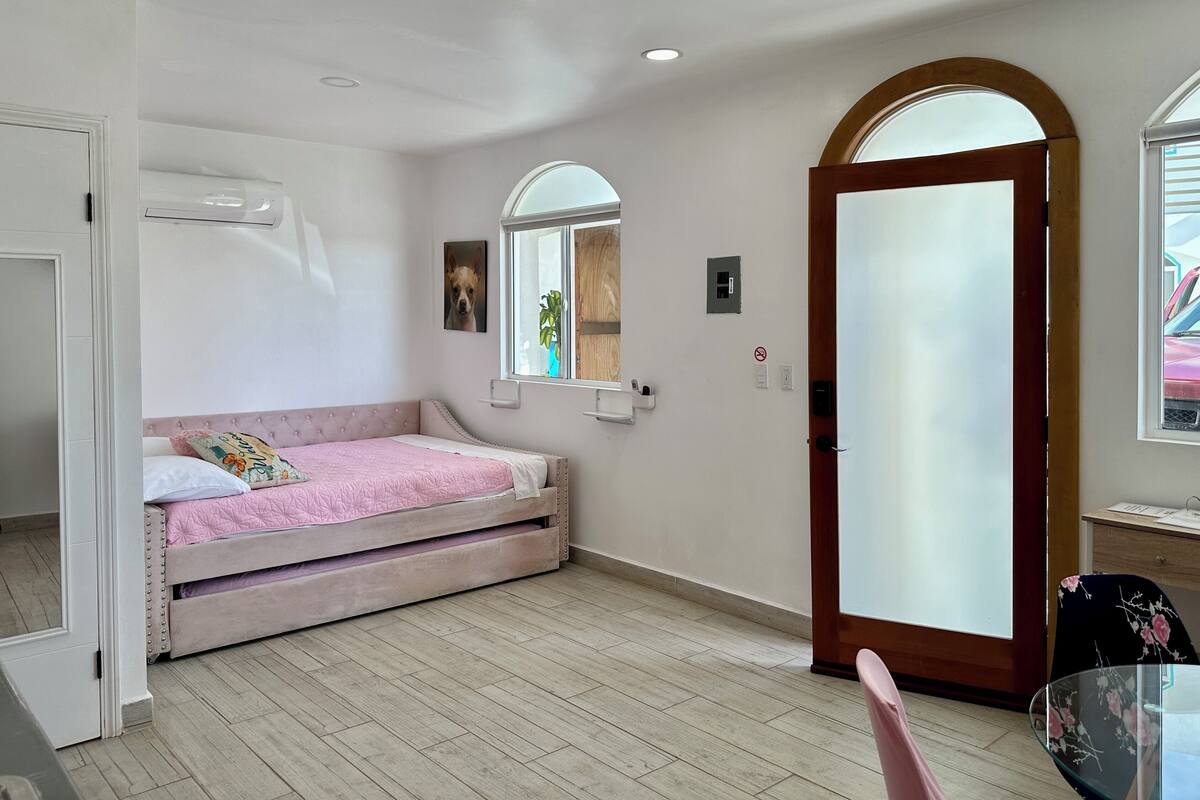 A bedroom with a bed, a window, a door, and a small table.