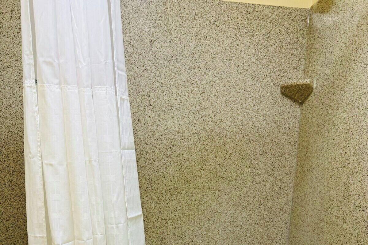 A bathroom with a bathtub, a shower curtain, and a towel hanging on the tub.