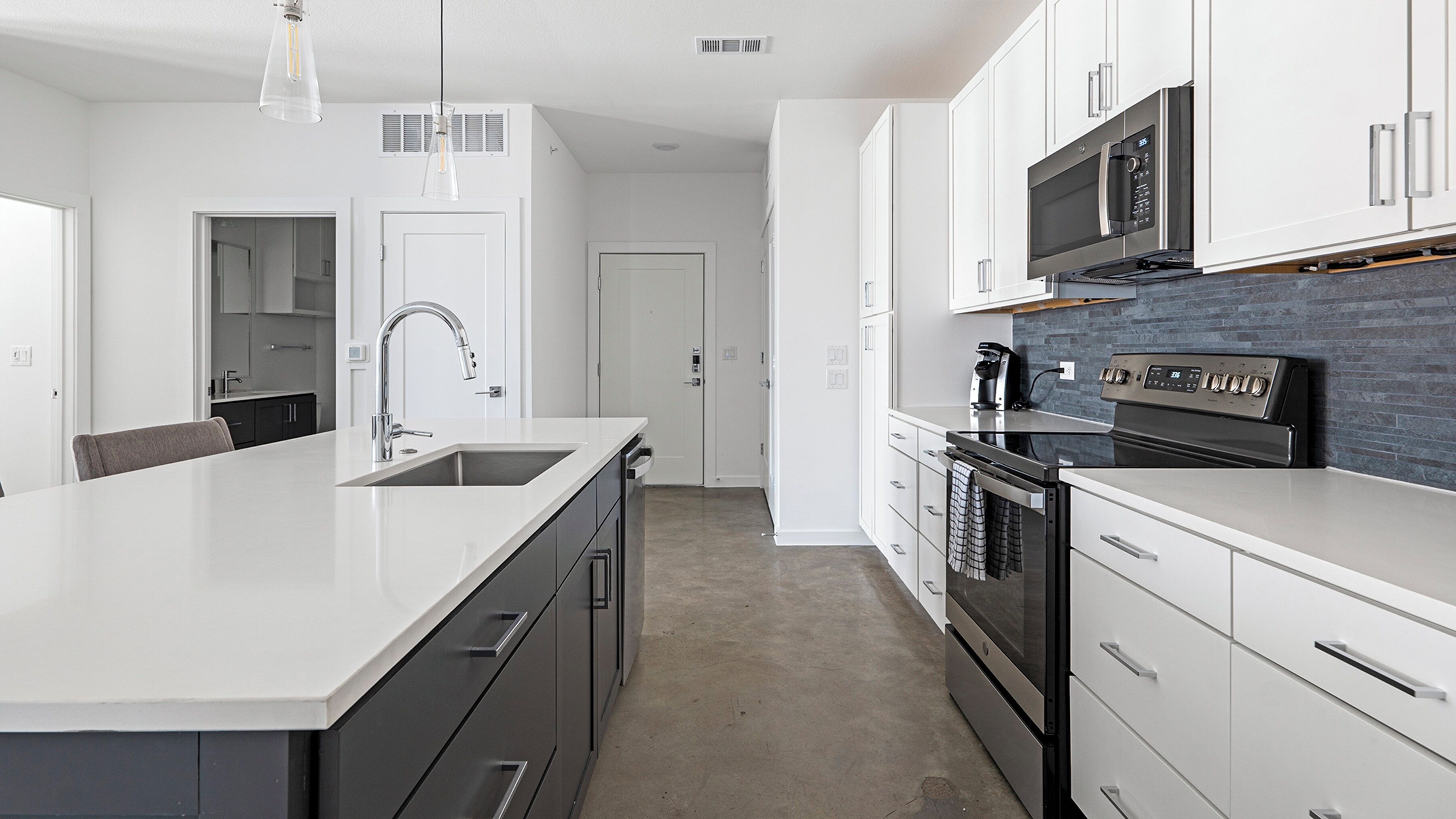 A modern kitchen with a central island, stainless steel appliances, and a backsplash.