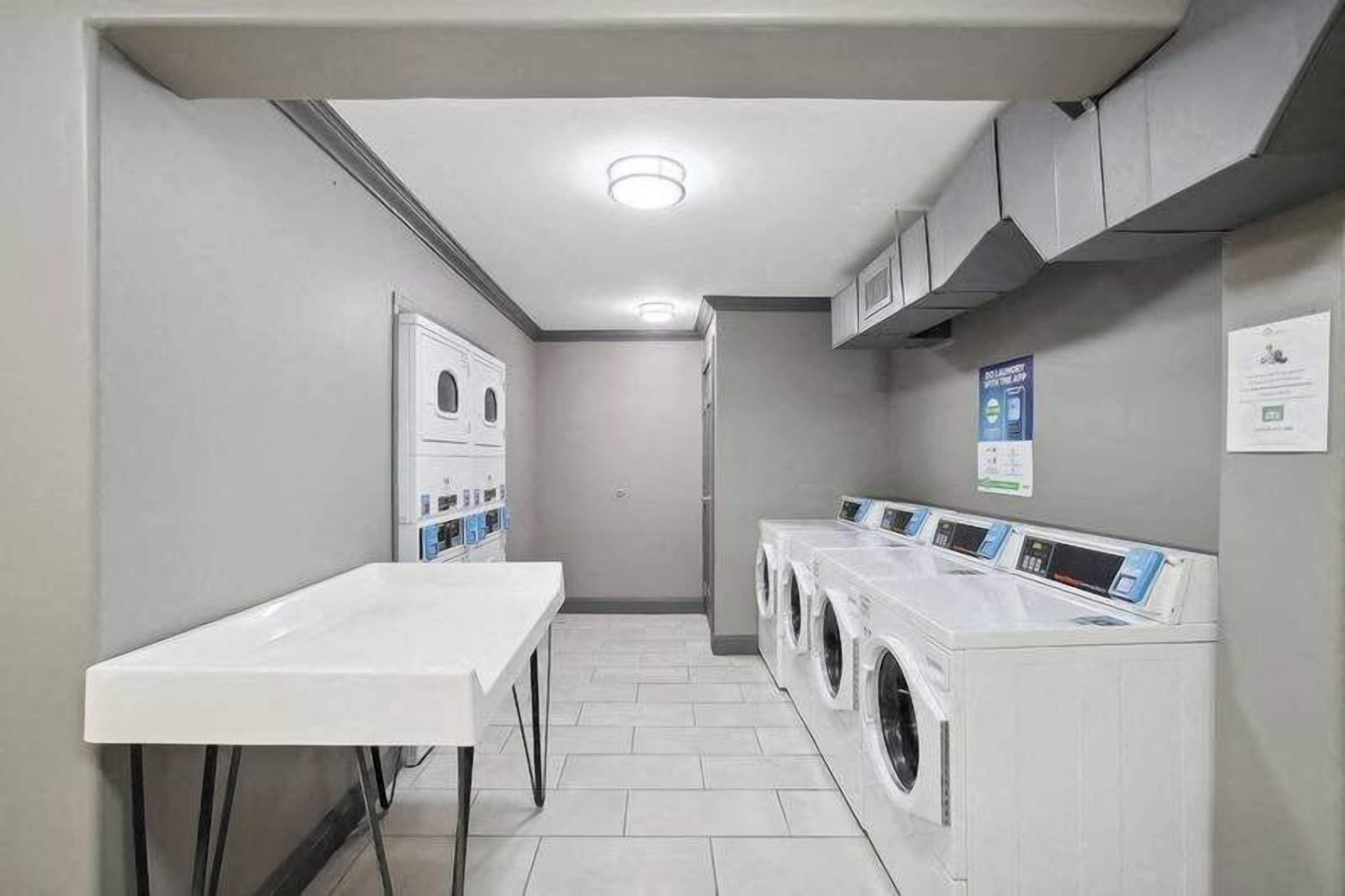 A laundry room with a table, washing machines, and cabinets.
