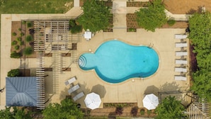 Vista aerea di una zona piscina con lettini, un'area salotto coperta e un piccolo solarium.